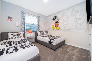 基西米3131-108FV STOREY LAKE, CONDO 3/2 LAKE VIEW的一间卧室配有两张床和一张米基老鼠壁画 更多17张照片