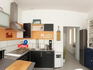 une cuisine avec des armoires noires et un mur orange et blanc dans l'établissement Duplex du Cloître 75m2, à Moissac