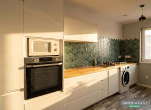 a kitchen with a microwave and a washer and dryer at Przytulne i ciepłe mieszkanie w spokojnej dzielnicy Opola in Opole
