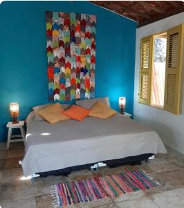 een slaapkamer met een bed met een kleurrijke muur bij Chalé Taiba in São Gonçalo do Amarante