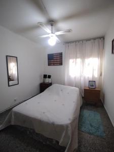 ein Schlafzimmer mit einem weißen Bett und einem Deckenventilator in der Unterkunft una caricia al alma in Neuquén