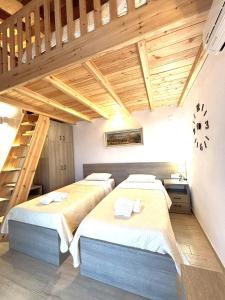 two beds in a room with wooden ceilings at Theo Two-Bedroom Apartment in Marathias