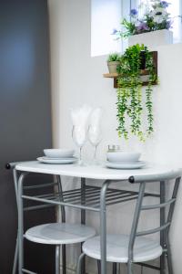 - une table blanche avec deux chaises et des verres dans l'établissement Cozy Studio Flat, 7mins from CENTRE, Parking, WiFi & Netflix, à Killingbeck 9 autres photos