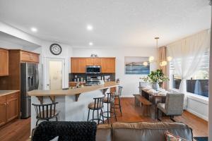 an open kitchen and living room with a counter and chairs at The Copperleaf Luxury Retreat with Hot tub in Calgary