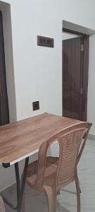 ein Holztisch mit einem Stuhl neben einer Tür in der Unterkunft Diya STAYS in Rāmpur Hāt