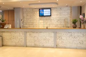 a bar with a tv on a brick wall at Alexander The Great Hotel in Laganas