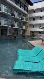 een zwembad met groene stoelen voor een gebouw bij Bela Vista Residence Piscina Privativa in Porto De Galinhas