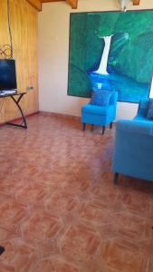 a living room with two blue chairs and a television at cabaña milita in Chile Chico