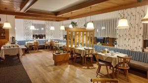 a dining room with tables and chairs and pendant lights at Haus Alpenfriede in Weissensee