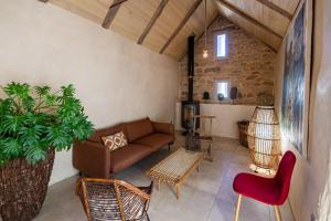 ein Wohnzimmer mit einem Sofa, Stühlen und einer Pflanze in der Unterkunft Les Terrasses de MAJORAC - Le Cottage in Bozouls