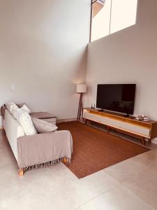 a living room with a flat screen tv and a couch at Casa Vista Serrana in São Pedro