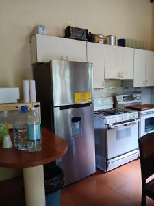 a kitchen with a stainless steel refrigerator and a table at Jardín de Los Sueños Quinta San Felipe in Cataltzul