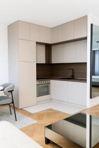 ポドゴリツァにあるWhite Lounge Haustorの白いキャビネット、椅子、テーブル付きのキッチンが備わります。