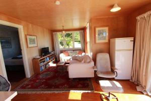 Una sala de estar con un sofá y un refrigerador. en Estuary View - Peaceful Onekaka Retreat, en Onekaka