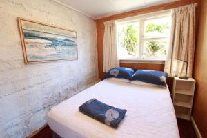 Un dormitorio con dos camas con almohadas azules y una ventana. en Estuary View - Peaceful Onekaka Retreat, en Onekaka