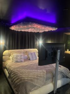 a bedroom with a large bed with purple lights at L'écrin Secret Suite & NETFLIX Aubagne-Cassis-Marseille in Aubagne