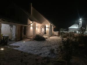 une maison la nuit avec de la neige au sol dans l'établissement Lapillo Vendégház, à Köveskál