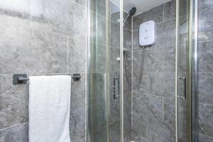 une salle de bain avec une douche avec une porte vitrée dans l'établissement Cozy Studio Flat, 7mins from CENTRE, Parking, WiFi & Netflix, à Killingbeck