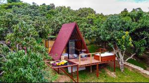 una pequeña casa con techo rojo en un bosque en Glamping Entre Mangos, en La Mesa 9 fotos más
