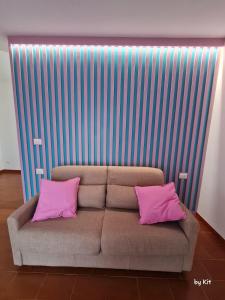 Pan Kit RoomS في أَويستا: أريكة مع وسادتين ورديتين في الغرفة