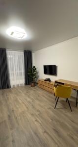 een woonkamer met een tafel en een gele stoel bij Sunset apart in Kremenets