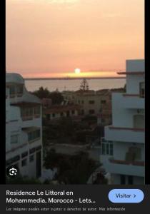 una puesta de sol sobre una ciudad con edificios y el océano en Resedence lettoral, en Mohammedia 1 foto más