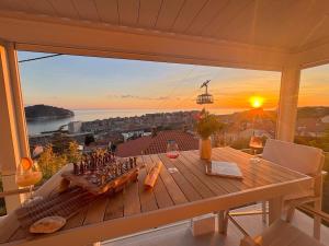 a table on a balcony with a view of the sunset at Villa D' Republic Dubrovnik - Infinity Pool & Old Town Views in Dubrovnik