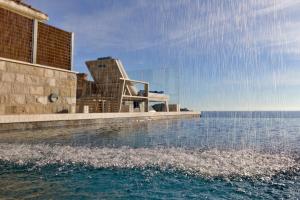 a swimming pool next to a building next to the water at Villa D' Republic Dubrovnik - Infinity Pool & Old Town Views in Dubrovnik