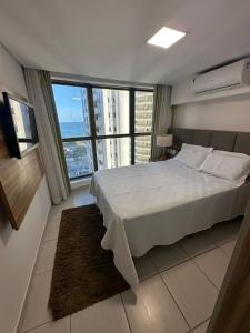 ein Schlafzimmer mit einem großen Bett und einem großen Fenster in der Unterkunft Beira Mar Boa Viagem Beach Class Executive in Recife