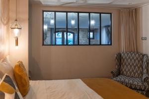 ein Schlafzimmer mit einem Bett, einem Stuhl und einem Fenster in der Unterkunft Les Terrasses de MAJORAC - La Grange in Bozouls