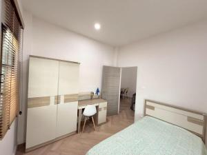 a bedroom with a bed and a desk in it at Tropical home close to nature and city in Ban Mai I