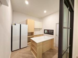a kitchen with a white refrigerator and wooden cabinets at Tropical home close to nature and city in Ban Mai I