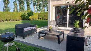un patio avec des chaises, une table et un grill dans l'établissement Chambre Magnolias, à Saint-Sauveur-dʼÉmalleville