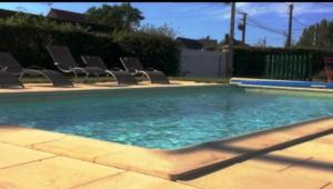 - une piscine avec des chaises et de l'eau bleue dans l'établissement chambre d'hôte Léonie, à Saint-Riquier 4 autres photos