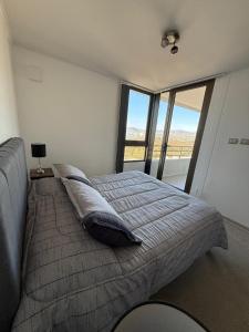 a bedroom with a large bed with a large window at alojamiento en coquimbo in Coquimbo