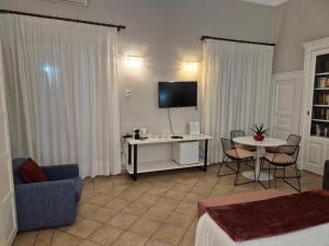 ein Wohnzimmer mit einem TV und einem Tisch mit Stühlen in der Unterkunft CENTRO STORICO HOME with terrace in Catania + 24 Fotos