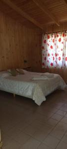 ein großes Bett in einem holzgetäfelten Zimmer mit Vorhängen in der Unterkunft Complejo Del Bosque in El Bolsón