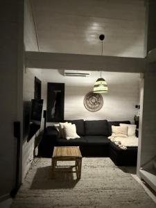 un soggiorno con un divano nero e un tavolo di Villa Laiskajaakko a Vimpeli