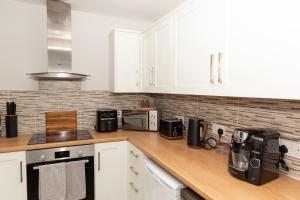 een keuken met witte kasten en een houten aanrechtblad bij The Terminus Loft in Conisbrough