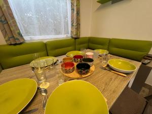 a table with yellow chairs and a green couch at Mobile Home Camping Paradis in Trédrez