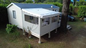 un abri blanc avec un toit à côté d'un arbre dans l'établissement Mobile Home Camping Paradis, à Trédrez