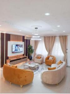 a living room with two couches and a tv at Epic Apartment in Abuja