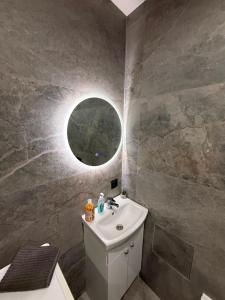 y baño con lavabo y espejo redondo. en Boris Heven Relax, en Daugavpils