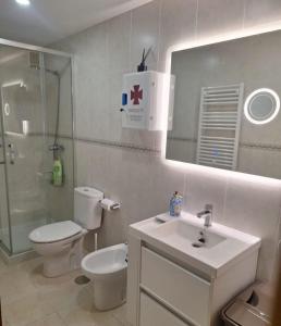a bathroom with a toilet and a sink and a mirror at LUARCAPLAYA APARTAMENTO Plazas de garaje incluidas in Luarca +54 photos