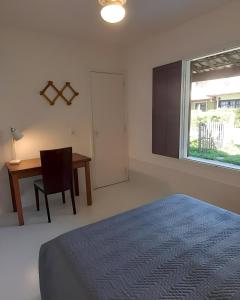 um quarto com uma cama, uma escrivaninha e uma janela em Linda casa para temporada no Peró/Cabo Frio em Cabo Frio mais 10 fotografias