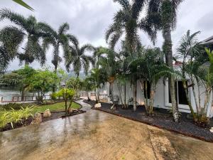 una casa con palme accanto a un corpo d'acqua di Tropical Lakeview Villa I Bangtao Beach a Ban Lum Fuang