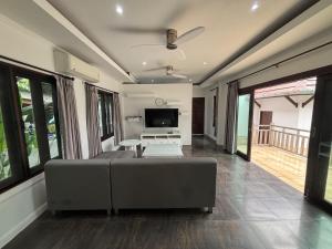 un soggiorno con divano e TV a schermo piatto di Tropical Lakeview Villa I Bangtao Beach a Ban Lum Fuang