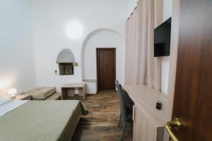 a room with a bed and a desk with a television at Agriturismo Marzilio in Ficarra