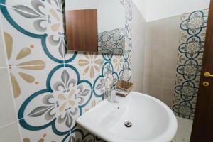a bathroom with a white sink and a flower patterned wall at Agriturismo Marzilio in Ficarra