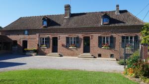 ein Backsteinhaus mit zwei Fenstern und einem Dach in der Unterkunft Chambres d'hôtes La Ferme du Scardon in Neufmoulin